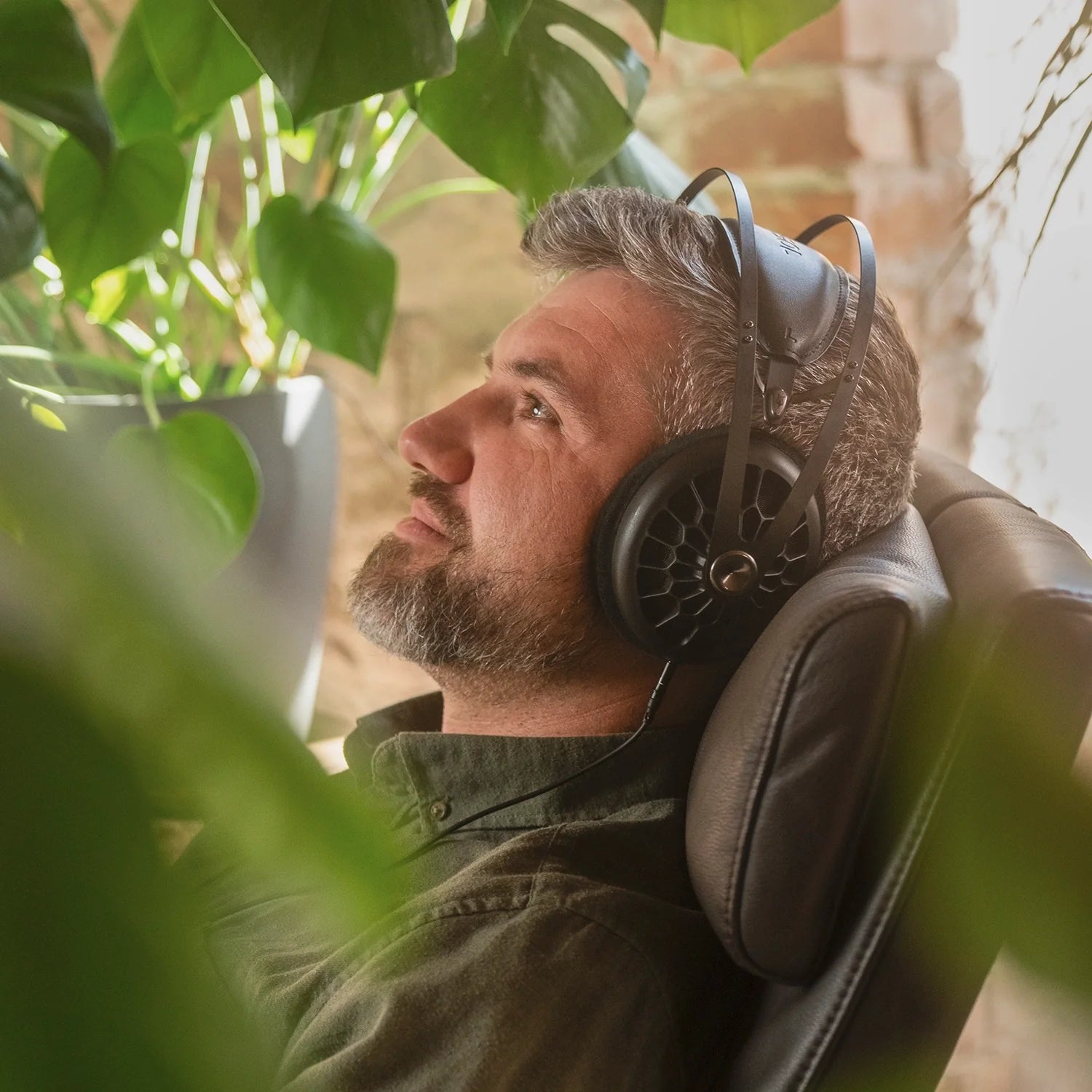 Meze Audio 105 AER best open back hifi audiophile premium headphones worn by man inside while sitting on an armchair 